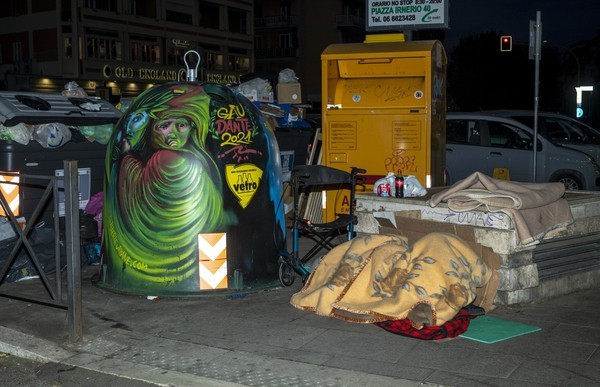 un clochard dorme accanto alla campana dipinta dall'artista Alberto Marchetti