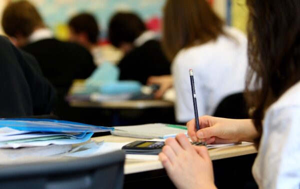 Ragazzi a scuola, di spalle, scrivono