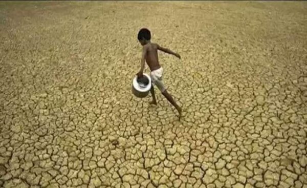 Un bambino su un suolo desertificato, alla ricerca dell'acqua