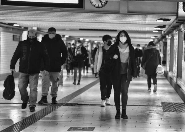 Un gruppo di persone cammina in una stazione con le mascherine FFP2